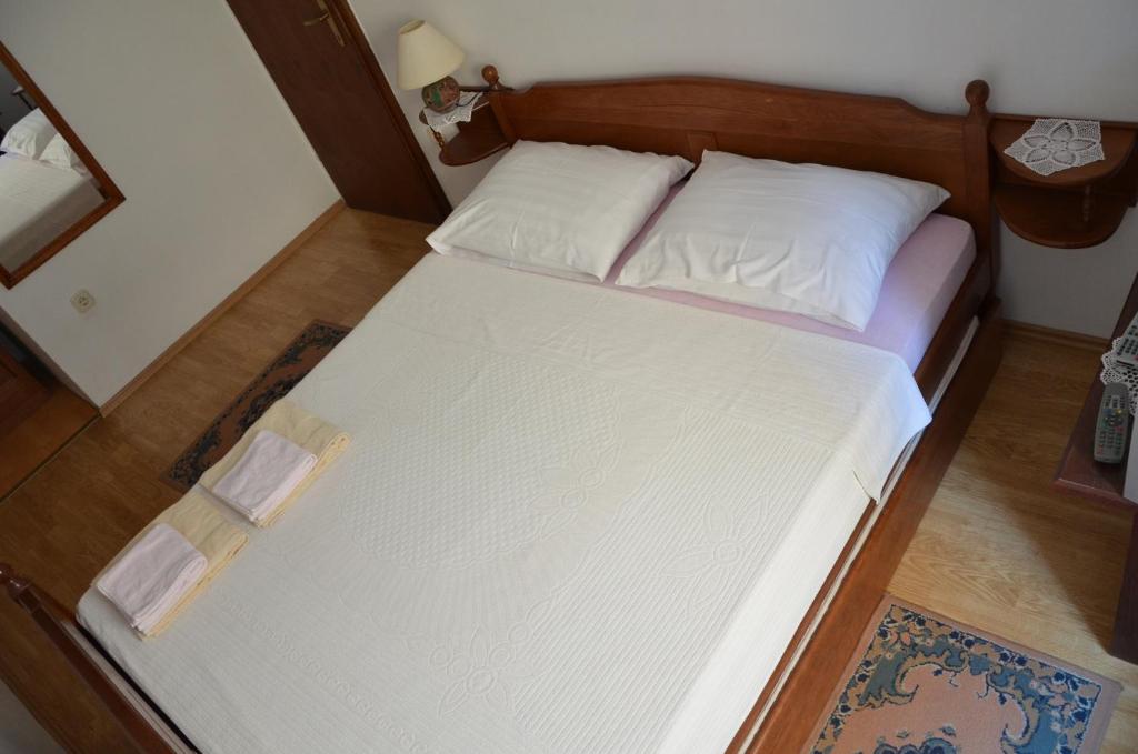 uma cama com lençóis brancos e almofadas num quarto em Apartments Ivanis em Vrsar