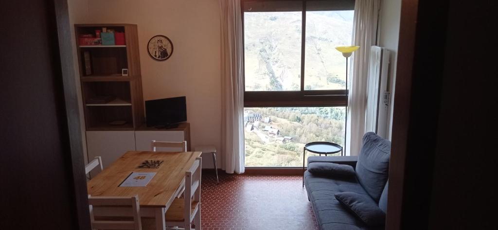 a living room with a couch and a table and a window at Appartement St Lary Soulan pied des pistes (le Pla d’Adet) 5 personnes in Saint-Lary-Soulan