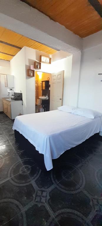 a large white bed in a room with a kitchen at finca casita el mirador in Medellín