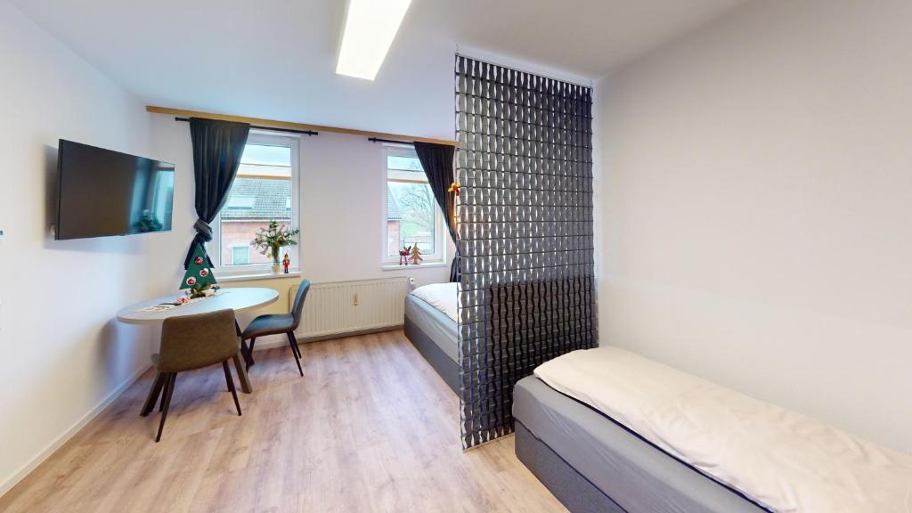 Cette petite chambre comprend un lit, un bureau et une table. dans l'établissement CozyWork Studio Apartment 7, à Hohenmölsen