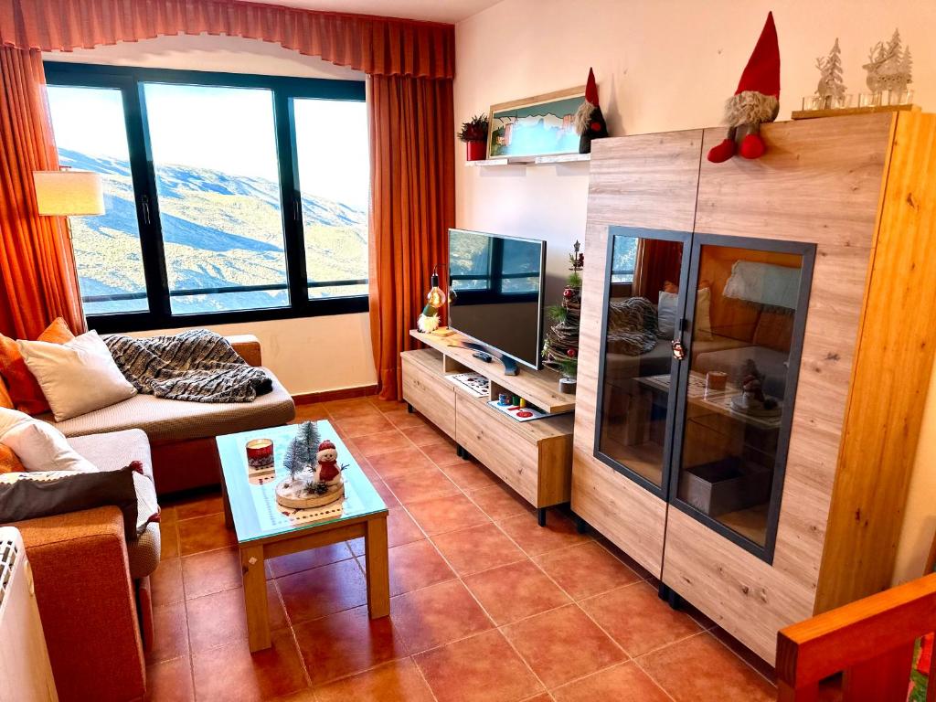 a living room with a couch and a tv at Monte Oiz con wifi y parking gratis in Sierra Nevada