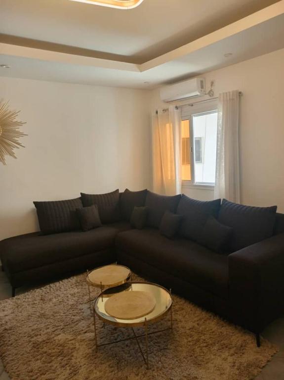 sala de estar con sofá negro y 2 mesas en Biagui en Dakar