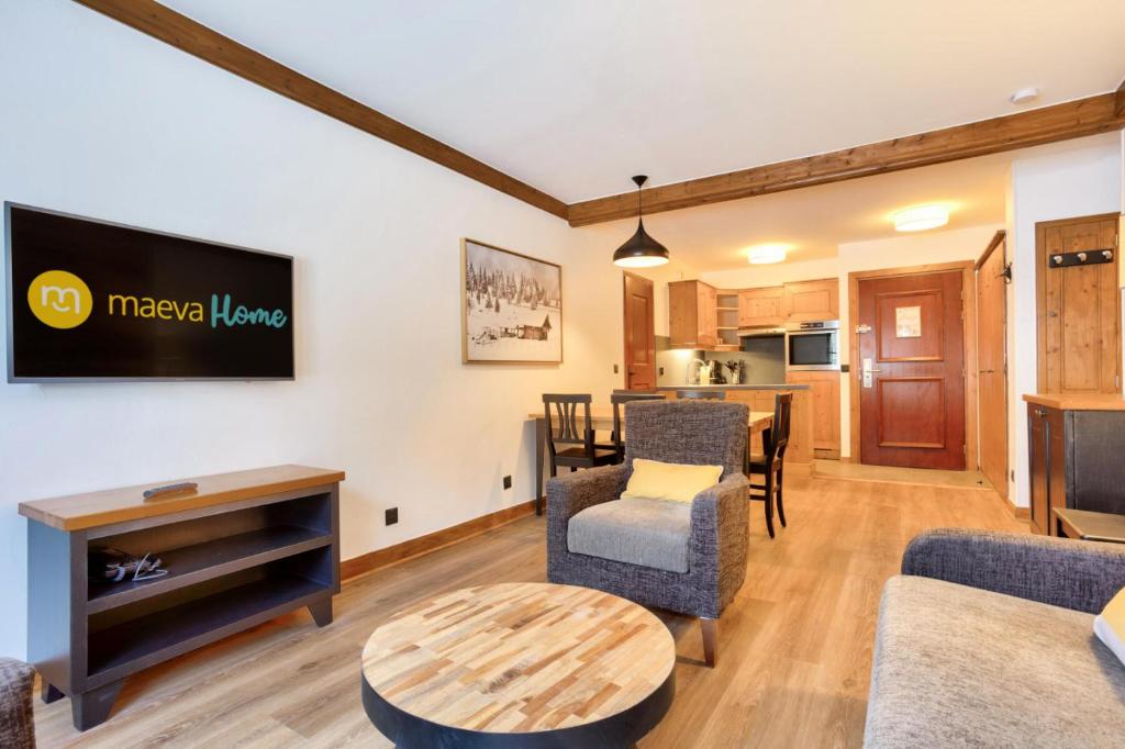un salon avec une télévision, une table et des chaises dans l'établissement Résidence Les Arcs 1950 Le Village - maeva Home - Appartement 3 pièces 6 personnes - Prestige MAE-5494, à Bourg-Saint-Maurice
