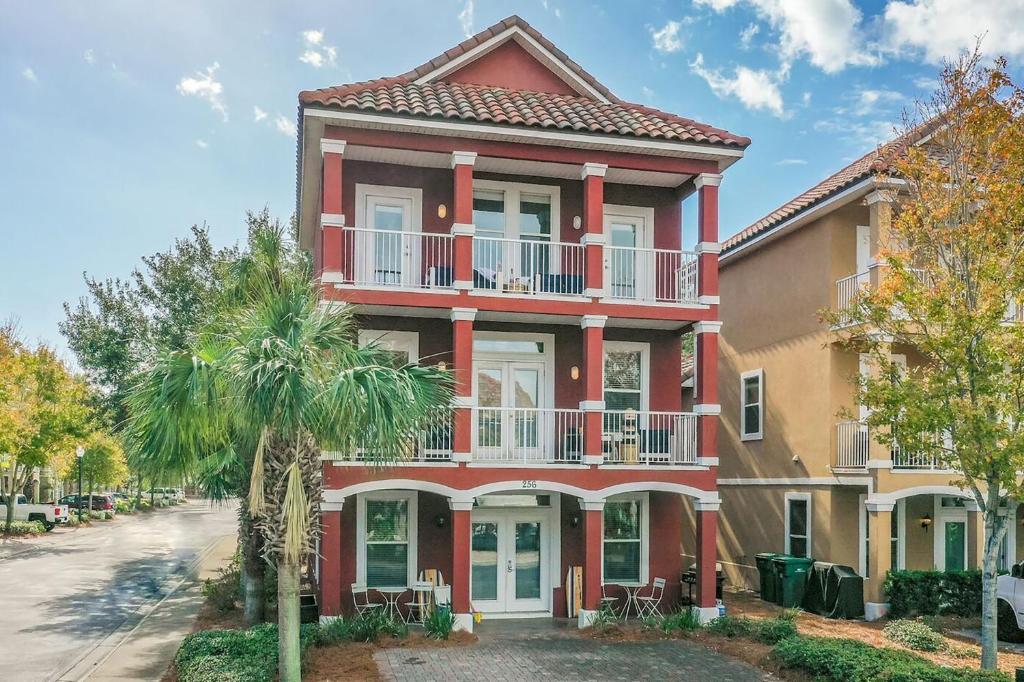a red house with a balcony on a street at Coral By AvantStay Gorgeous Three Story Home w Two Balconies in Destin