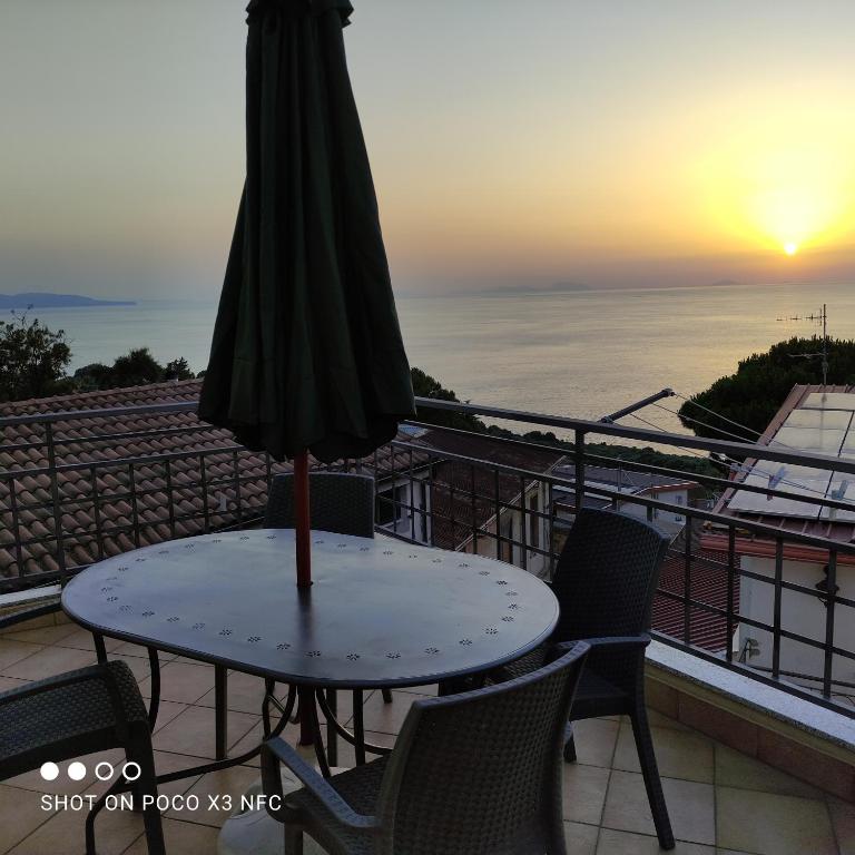 a table with an umbrella on a balcony with the sunset at B&B Vista Mare "Terrazzo" in Palmi
