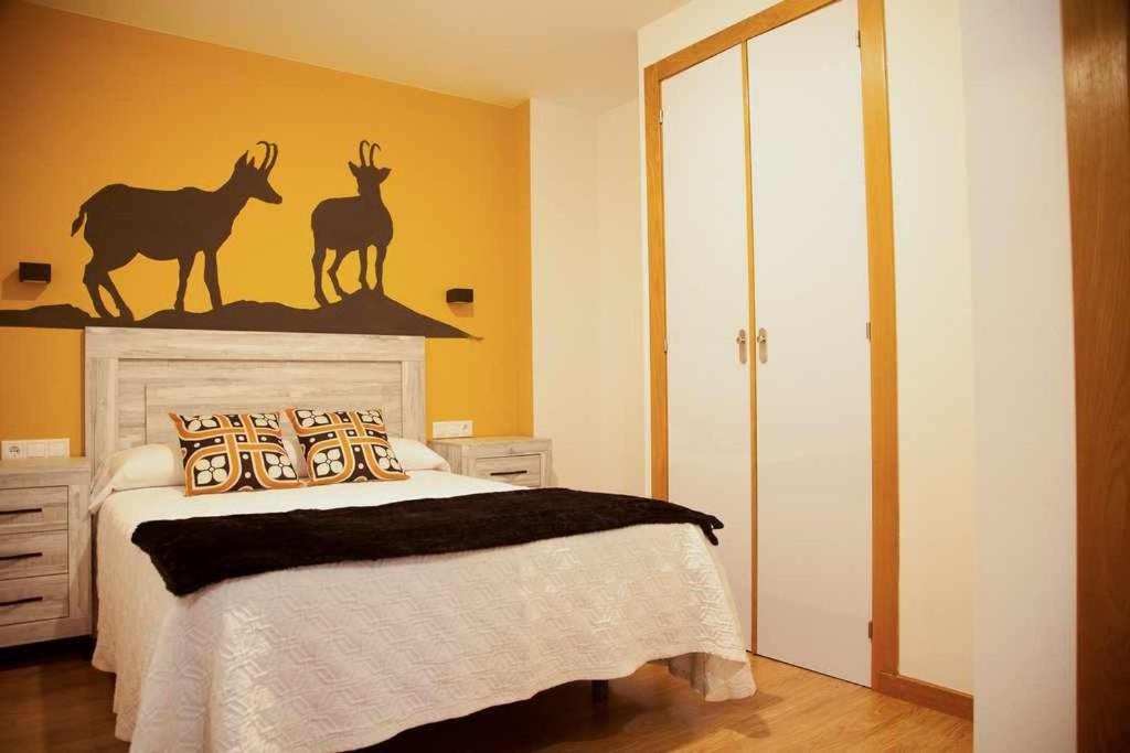 Schlafzimmer mit einem Bett mit Hirsch an der Wand in der Unterkunft Cumbres De Los Picos Apartamento Rebecos in Poo de Cabrales