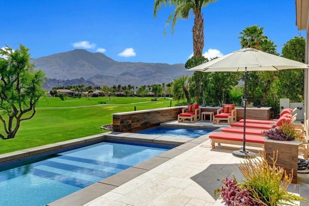 une terrasse avec une piscine, une table, des chaises et un parasol dans l'établissement Legends by AvantStay Stunning Golf Villa Featuring Spa Pool Fire-Pit, à La Quinta