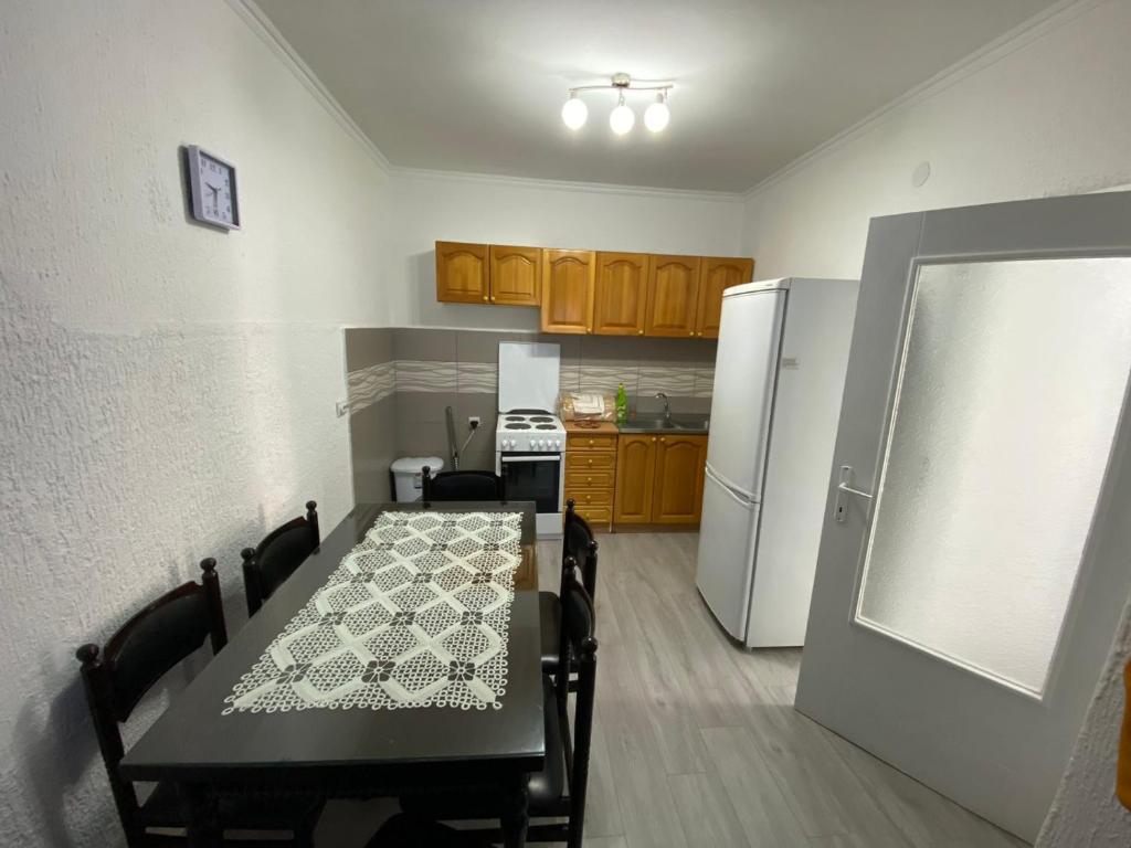 a kitchen with a table and a white refrigerator at Apartmani Popov in Vrbas