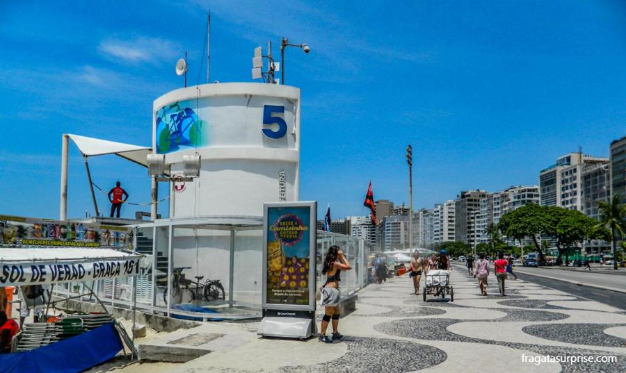 un grupo de personas caminando por una acera al lado de un edificio en Posto 5 Copacabana - quadra da praia 613, en Río de Janeiro