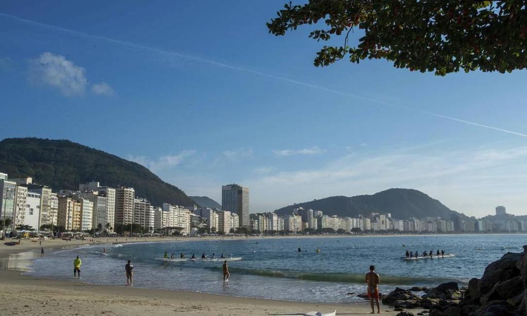 una playa con gente en el agua y edificios en Flat Copacabana quadra da praia 907, en Río de Janeiro