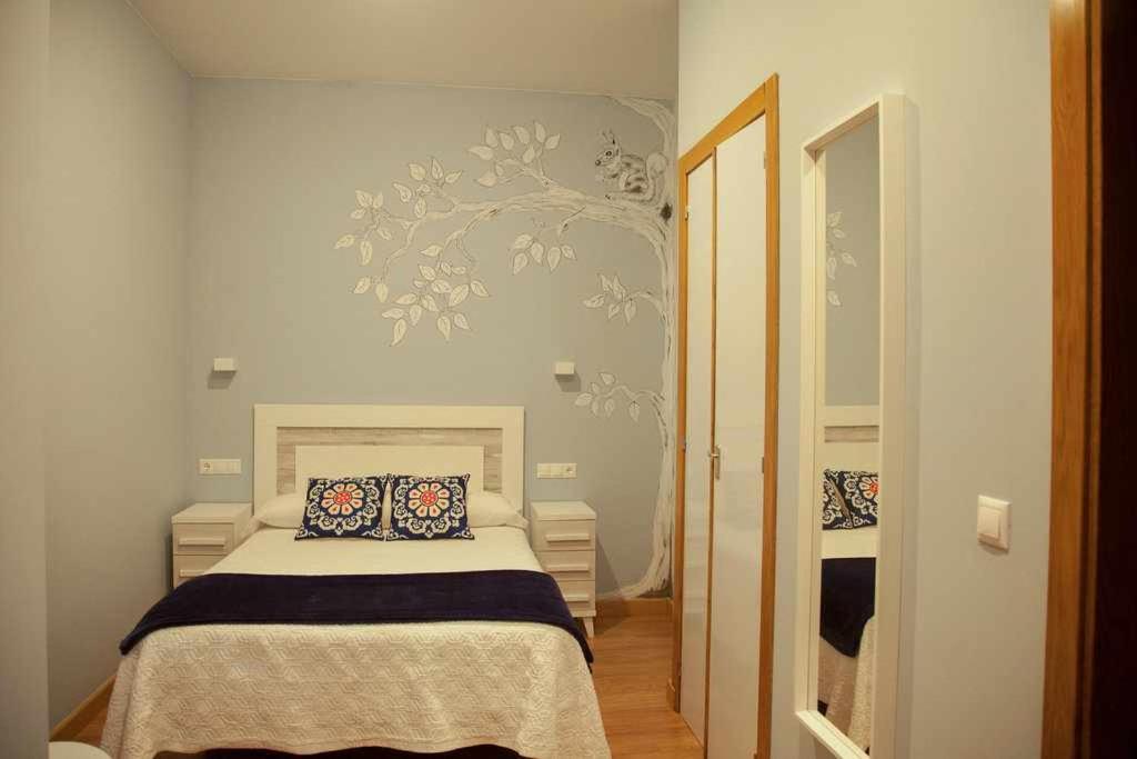 um quarto com uma cama e uma parede com um mural de árvore em Cumbres de los Picos Apartamento Urriellu em Poo de Cabrales
