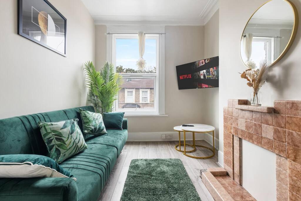 a living room with a green couch and a fireplace at Cosy 3 Bed Flat 15mins to Kings Cross in London