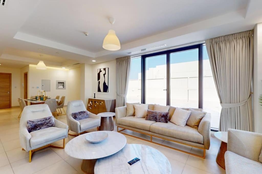 uma sala de estar com um sofá, cadeiras e uma mesa em Janayen Avenue - Locations no Dubai