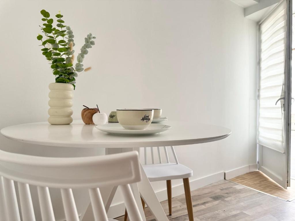 a white dining room table with a vase and chairs at Logement Entier au Centre Ville in Évreux