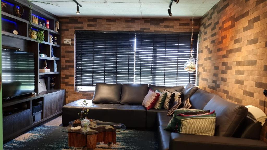 uma sala de estar com um sofá de couro e uma parede de tijolos em SUPER Conforto Praia Brava Balneario Camboriu em Itajaí