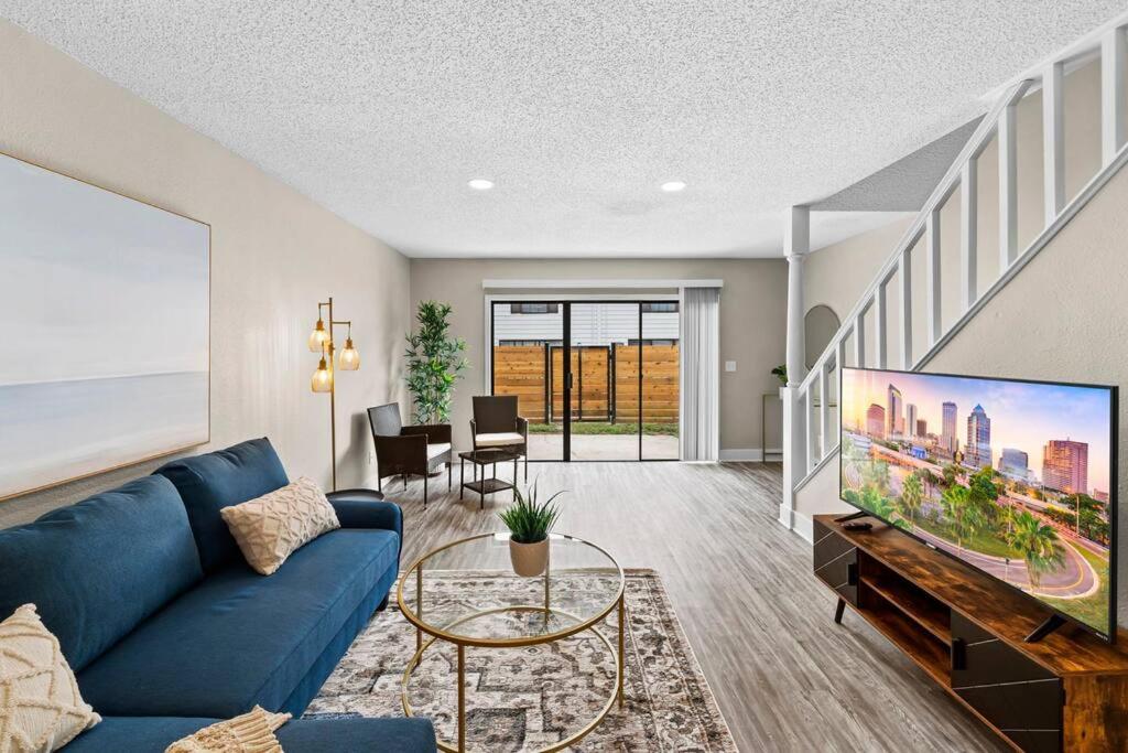 uma sala de estar com um sofá azul e uma televisão em Cozy Townhouse - Gym Pool Golf Fast WiFi 2B2B em Tampa