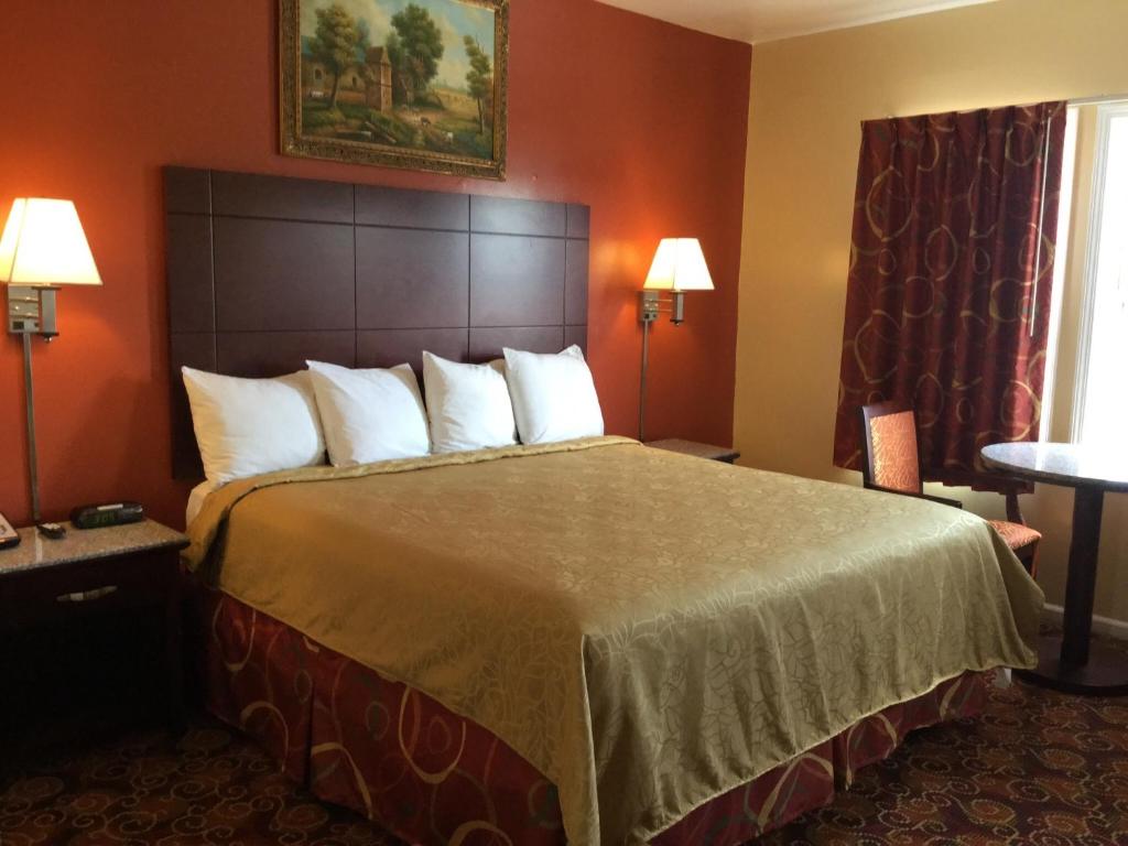 um quarto de hotel com uma cama grande com almofadas brancas em Red Carpet Inn-Bridgeton/Vineland em Bridgeton