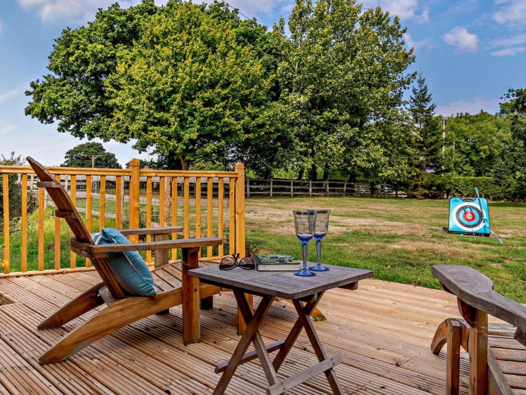 a wooden deck with a chair and a table with a wine glass at 2 Bed in Hailsham 89416 in Hailsham