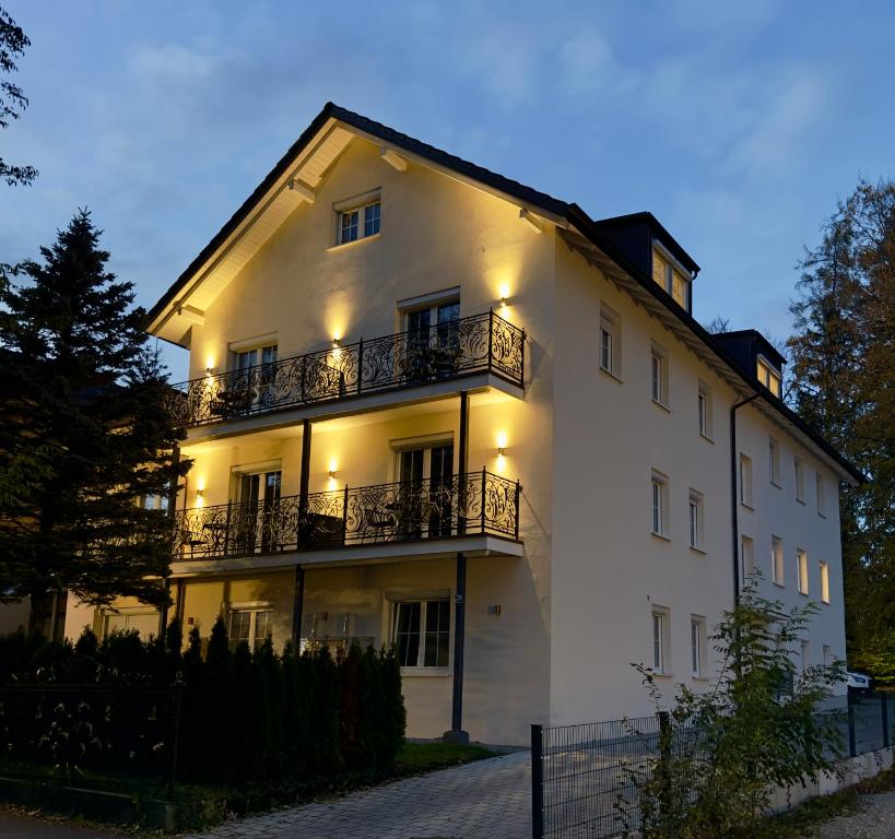 ein weißes Gebäude mit Balkon und Beleuchtung in der Unterkunft YUVA HOMES am Kurpark in Bad Wörishofen