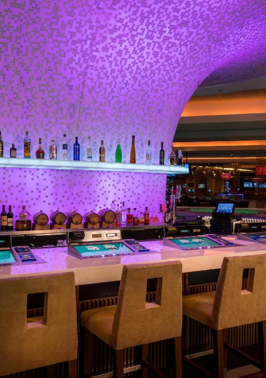 a bar in a casino with purple lighting at The LINQ Hotel and Casino in Las Vegas