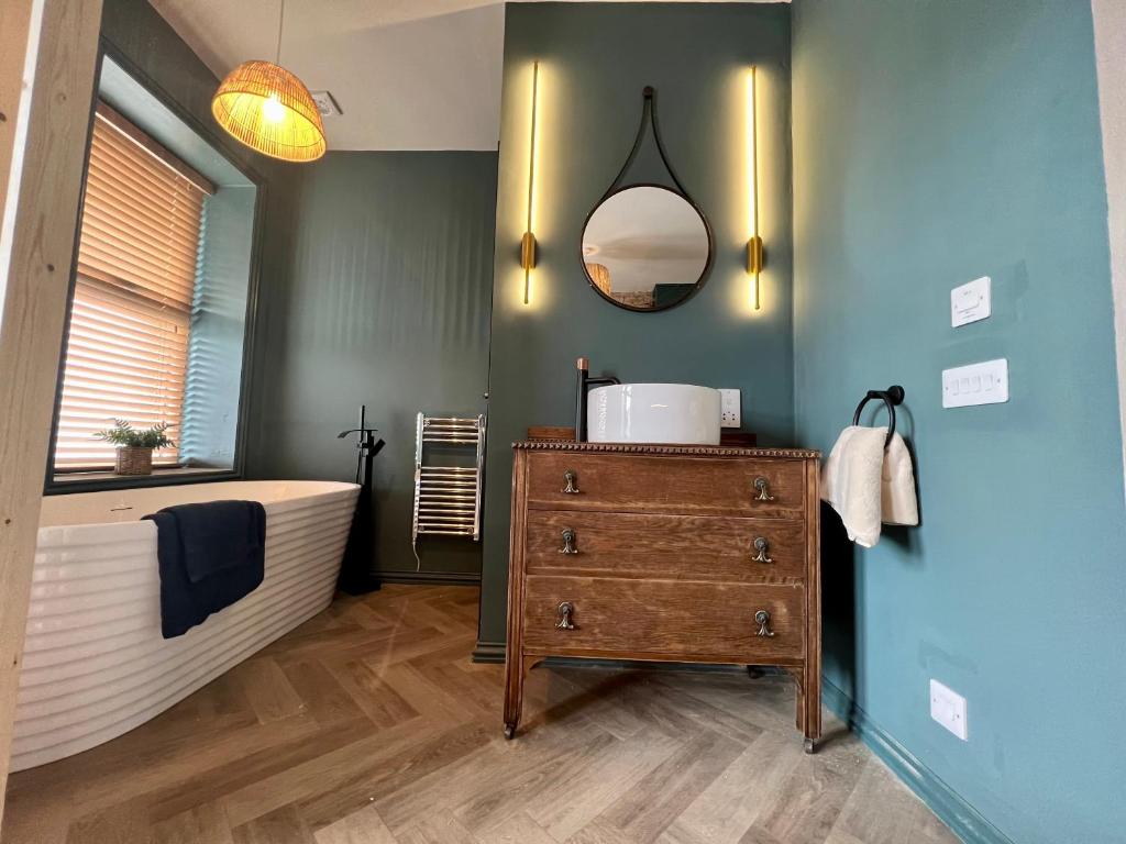 a bathroom with a bath tub and a wooden dresser at Lancaster Place 20 in Carnforth