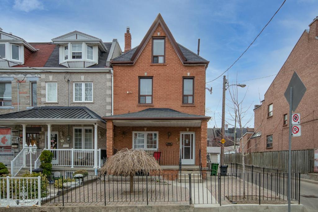une maison en briques avec une clôture devant elle dans l'établissement Cozy Home In Downtown Toronto!, à Toronto