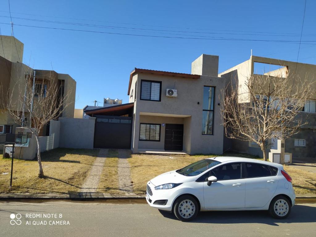 une voiture blanche garée devant une maison dans l'établissement Casa 3 dormitorios. - Barrio Valle Cercano, à Córdoba