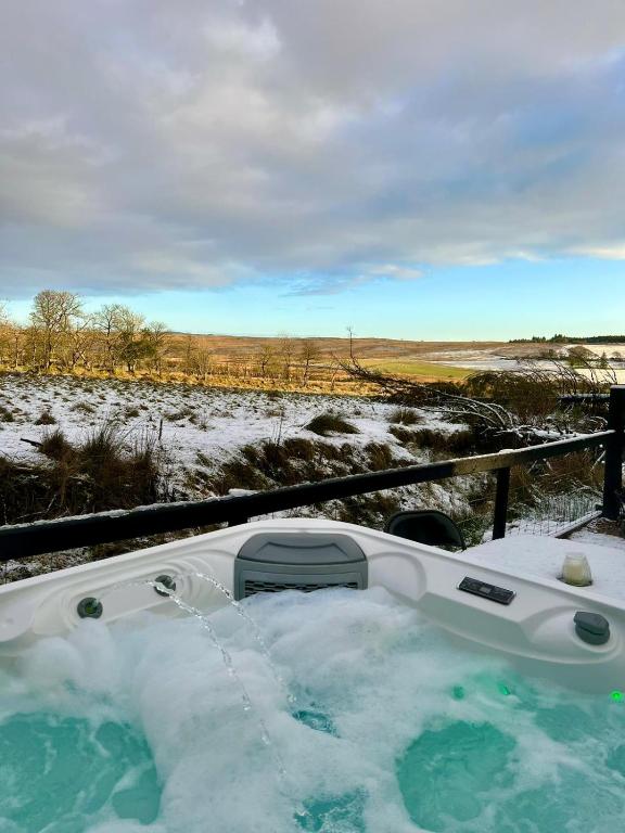 a jacuzzi tub with snow in a field at Speir dorcha cabin in Omagh