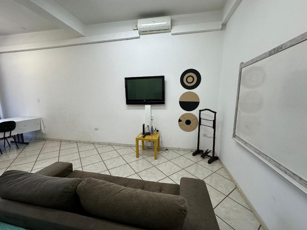 a living room with a couch and a white wall at Apartamento no Centro São João da Boa Vista in São João da Boa Vista