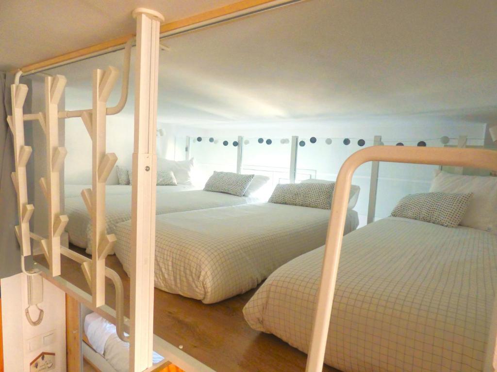 a bedroom with two bunk beds with white sheets at Apartamento Maribel a pie de pista in Sierra Nevada