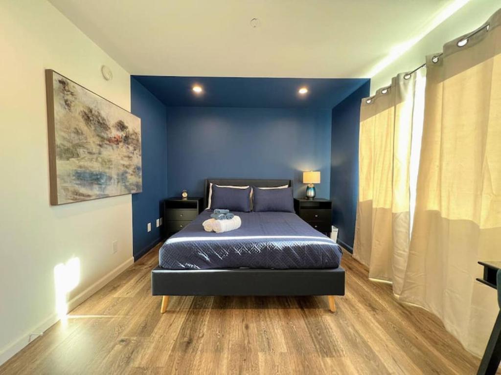 een slaapkamer met een bed met blauwe muren en houten vloeren bij Trendy 2BR Near Hollywood Hotspots - BR9 in Los Angeles