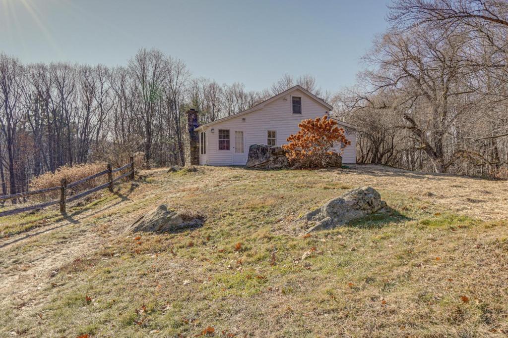 ein kleines weißes Haus auf einem Hügel mit einem Zaun in der Unterkunft Cozy Berkshires Cottage with 11 Private Acres! in Lee