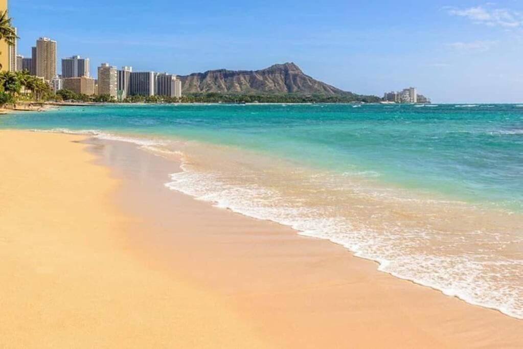 uma praia de areia com edifícios e o oceano em Brooks Beach Vacations Wyndham 4 Star Resort 1805 Waikiki em Honolulu