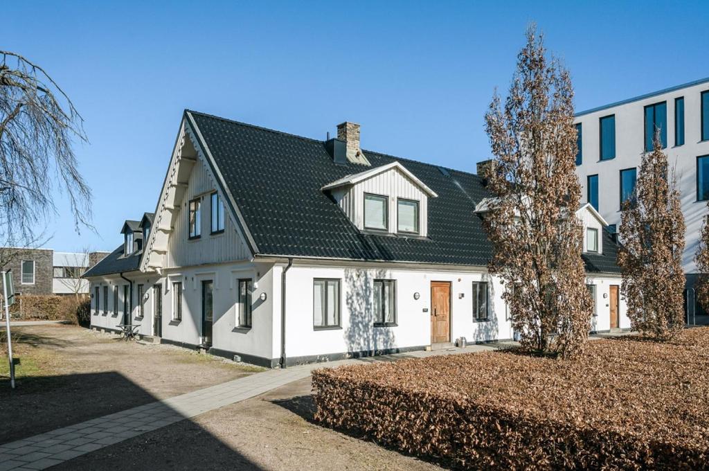 une grande maison blanche avec un toit noir dans l'établissement Bright apartment in park environment, à Lund
