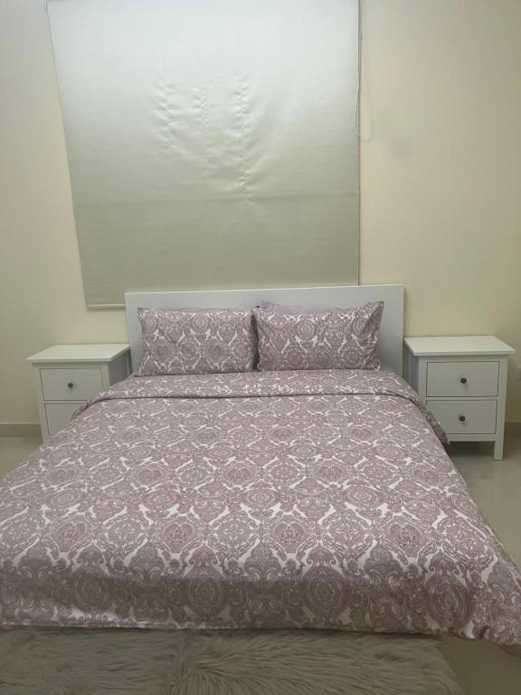 a bed with a purple comforter and two night stands at One bedroom apartment in Jimi in Al Ain