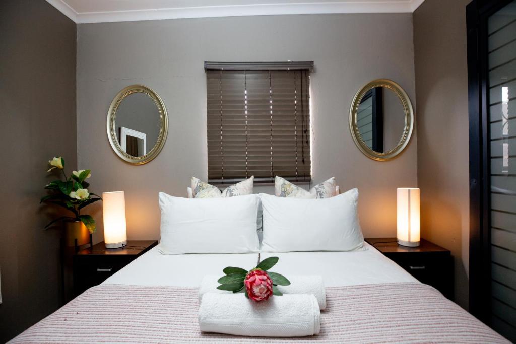 a bedroom with a large bed with two mirrors at URlyfstyle Cottage Near OR Tambo International Airport in Kempton Park
