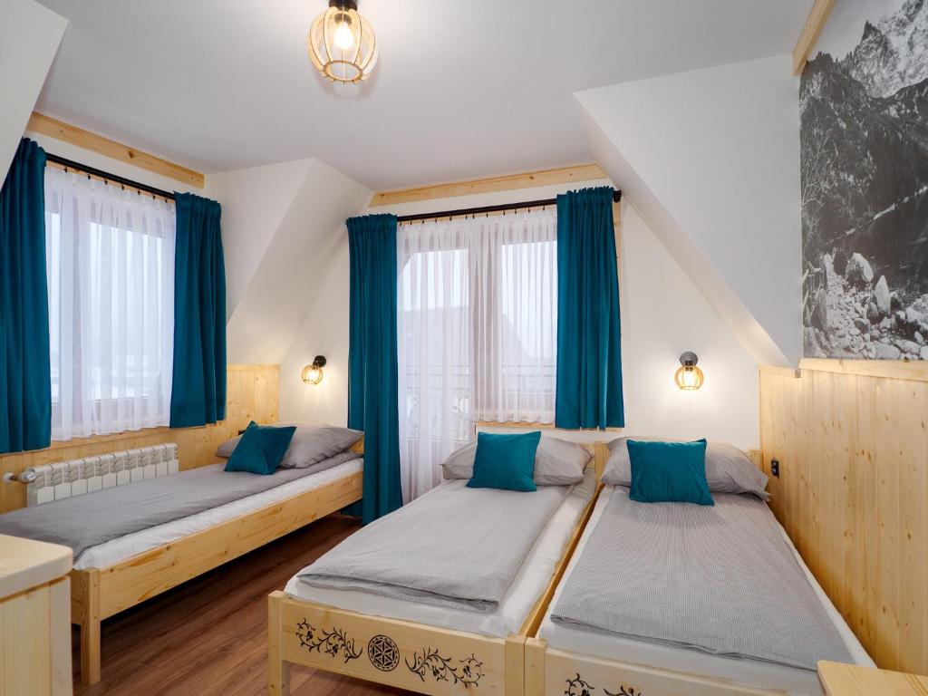 two beds in a room with blue curtains at Pokoje Andrzej i Krystyna Lukaszczyk in Małe Ciche