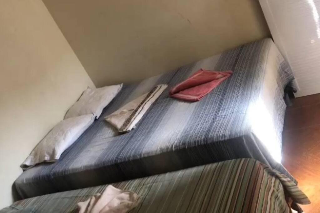 uma cama com duas almofadas num quarto em Casa - 70 metros da praia em Cruz