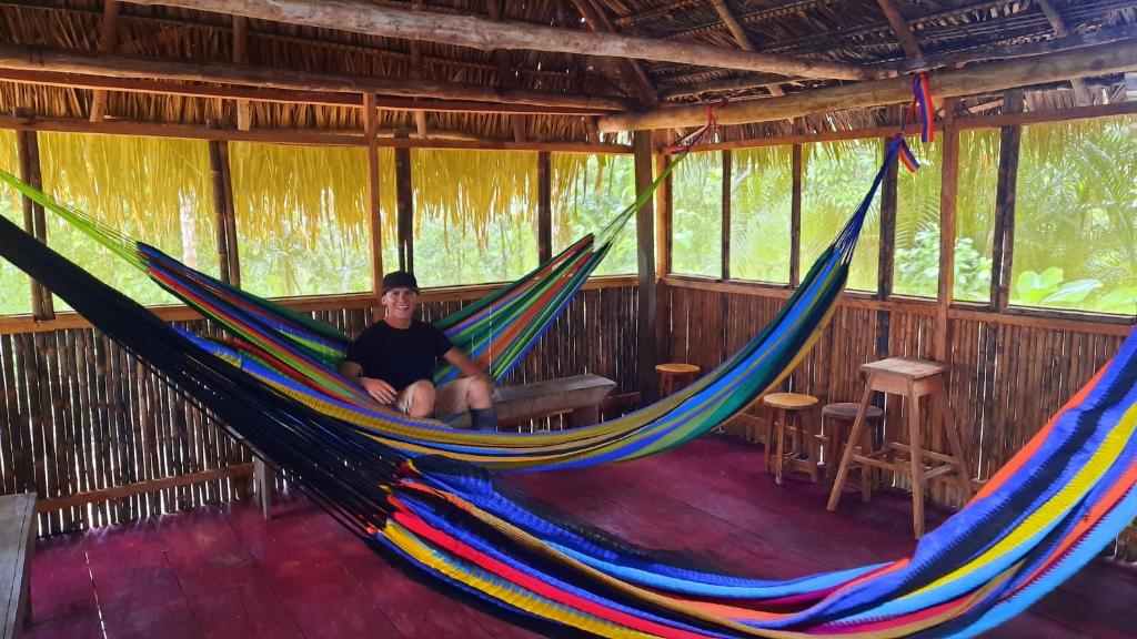 Eine Frau, die in einer Hängematte in einer Hütte sitzt in der Unterkunft ARAPARI AMAZON LODGE in Mazán