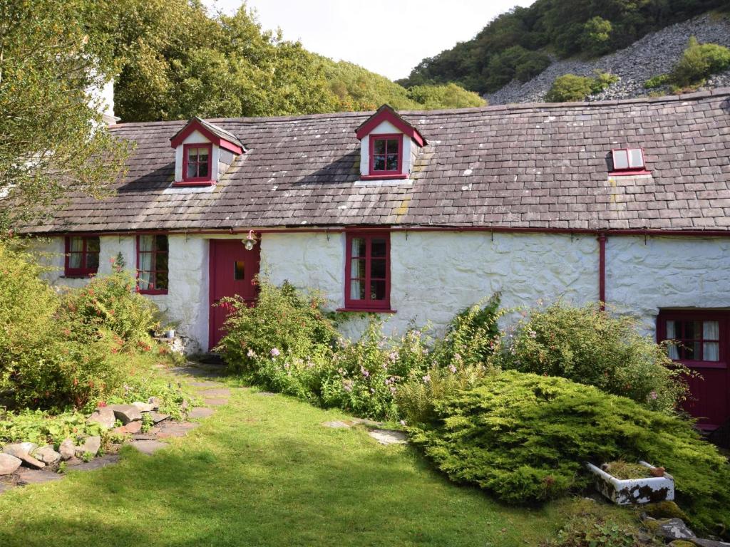 a white house with red windows in a garden at 3 Bed in Arthog 66579 in Arthog