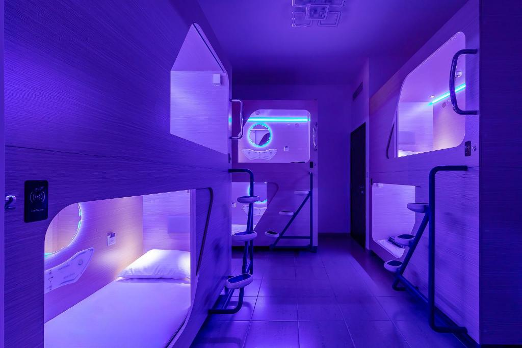 um quarto roxo com uma cama e dois bancos em Berloga Capsule JBR em Dubai