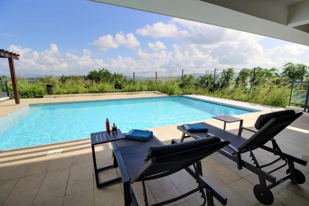 a swimming pool with two chairs and a table next to it at Appartement Sky Blue in Fort-de-France