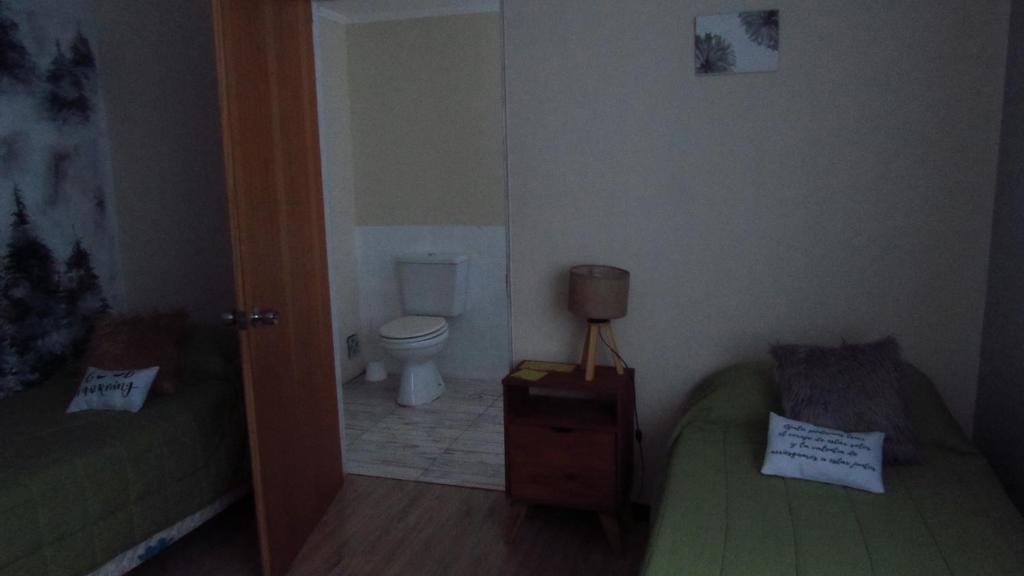 a bathroom with a toilet and a bed in a room at Berkana hostel Bariloche in San Carlos de Bariloche