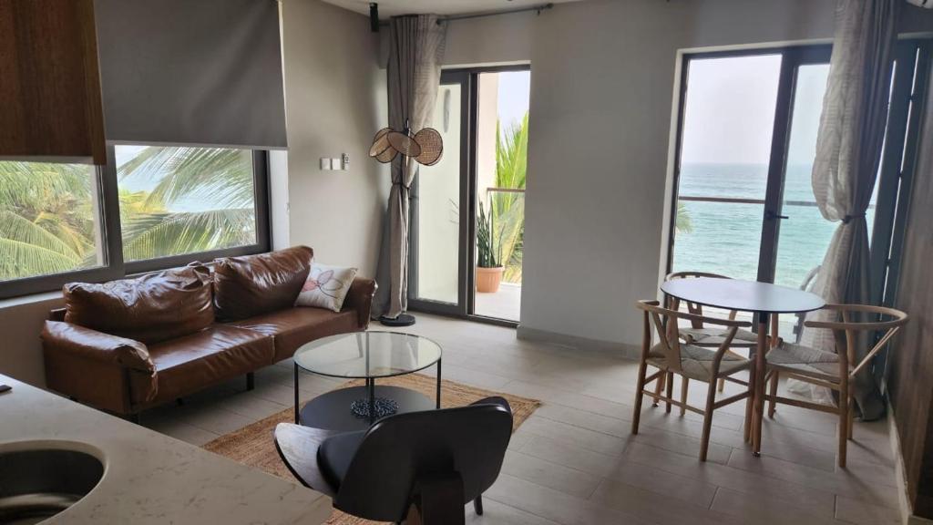 uma sala de estar com um sofá e mesas e o oceano em Serenity Terraces Beach, Hotel - Kokrobite em Kokrobite