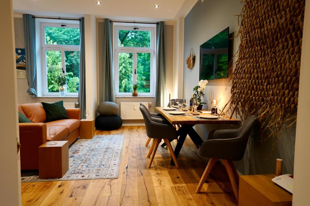 uma sala de estar com uma mesa e um sofá em EDLER WOHNRAUM Luxuriöses Stadtstudio mit Einbaukaffeevollautomat, Balkon, Netflix & Klimaanlage em Zwickau