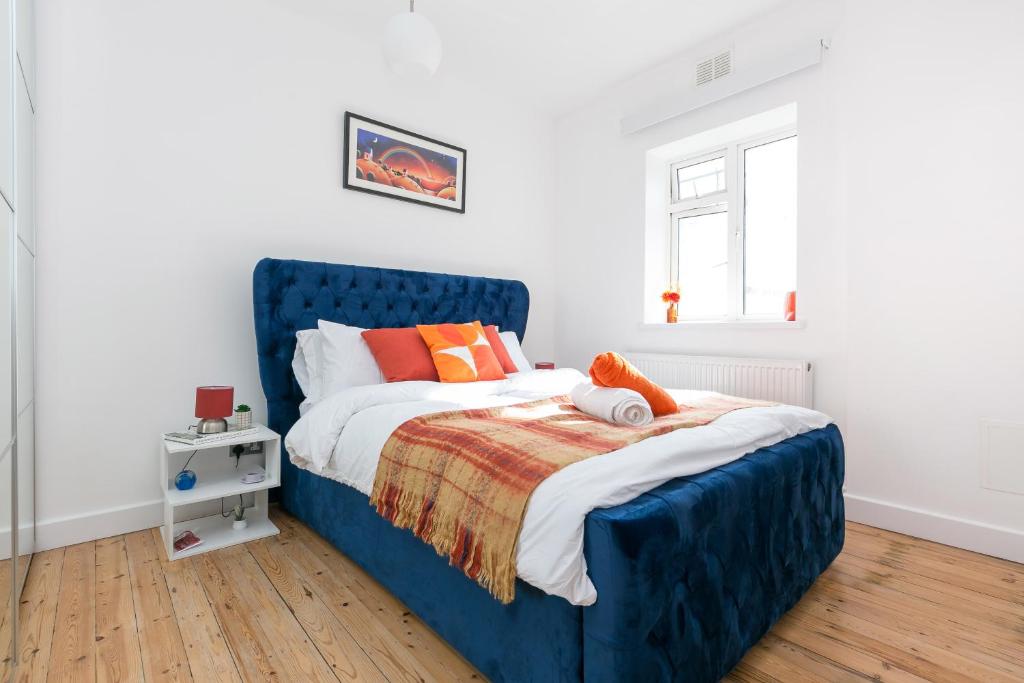 Bett mit blauem Kopfteil in einem Schlafzimmer in der Unterkunft Stylish, Cosy flat W/Parking in London, UK in Raynes Park