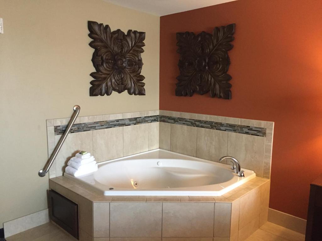 a bath tub in a bathroom with two wall arts at Grandstay Hotel & Suites Mount Horeb - Madison in Mount Horeb