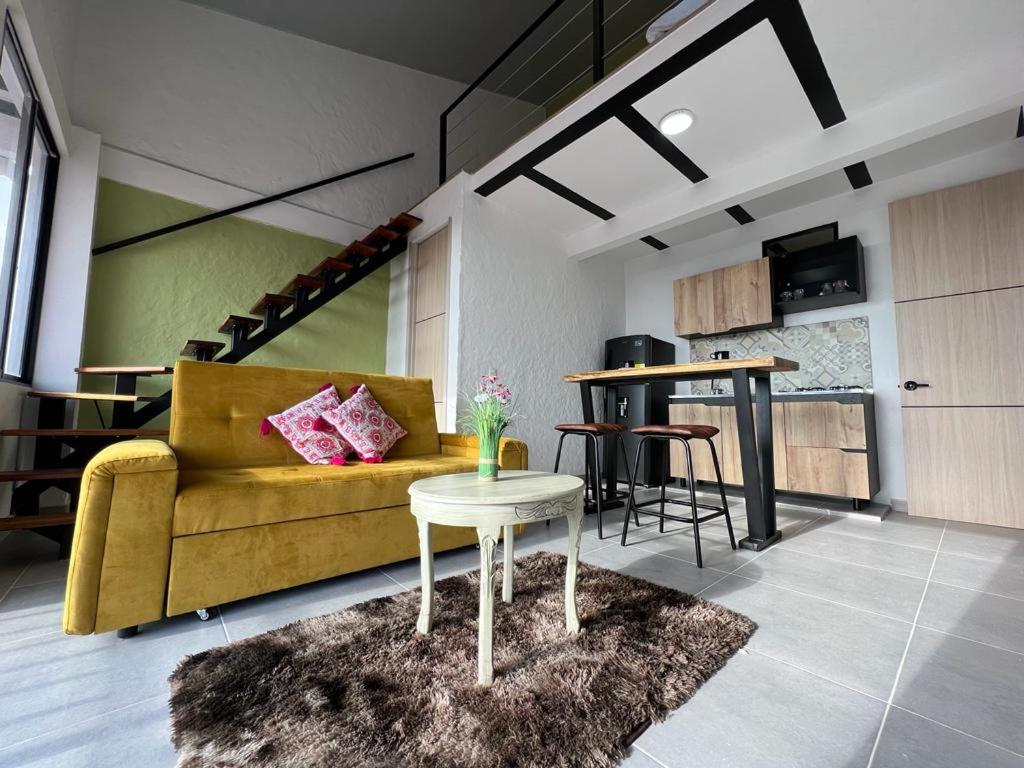 ein Wohnzimmer mit einem gelben Sofa und einem Tisch in der Unterkunft apartaestudios las astromelias salento in Salento