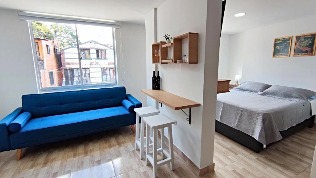ein Schlafzimmer mit einem blauen Sofa, einem Bett und einem Tisch in der Unterkunft Villa Quintero apartamentos in Santa Rosa de Cabal