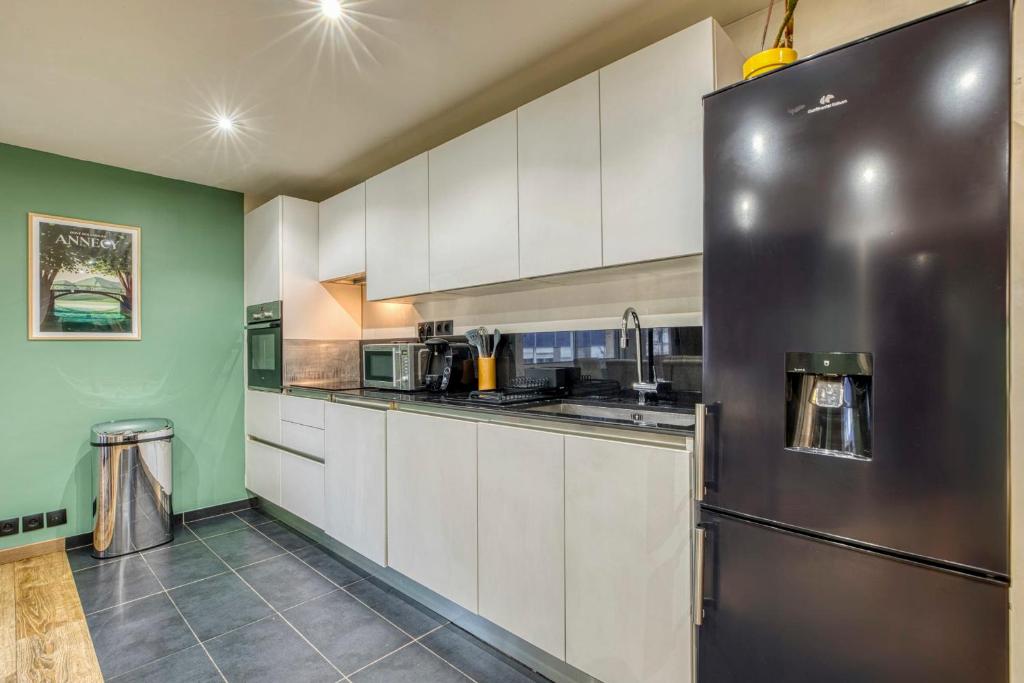 a kitchen with white cabinets and a stainless steel refrigerator at Spacious and cosy flat in Annecy